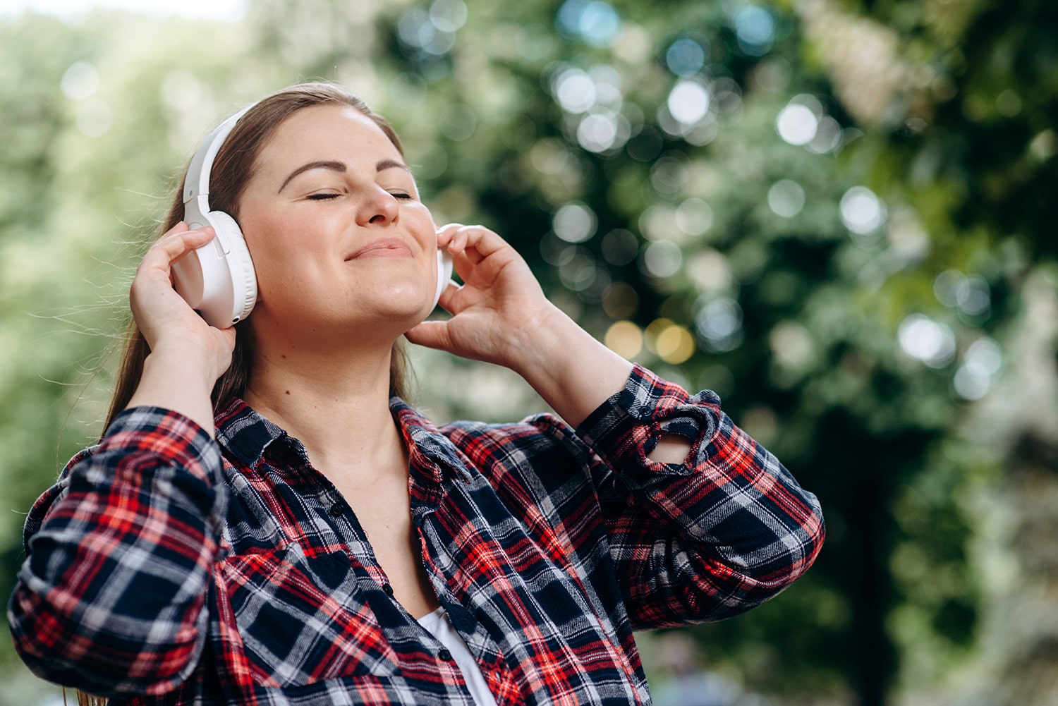 Nöjd kvinna som njuter av musik i en park. Tarmbakterierna och deras signalsubstanser har ett nära samarbete som påverkar hela din hälsa. När allt är i balans ger det harmoni till magen.